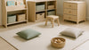Bright Nordic-style kids’ room with child-height book storage, low open bins, a bench-like chair, and a soft play area arranged for safe, space-conscious baby-to-toddler organization.