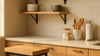 Hero kitchen scene showing coordinated storage furniture and countertop accessories with natural wood, matte metal, and clutter-free organization.