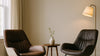 Editorial living room scene comparing two mid-century style lounge chairs with different material and finish quality, shown at believable room scale under soft natural light.