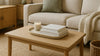 A photorealistic living room with budget-friendly stylish accessories: a linen sofa, textured throw, ceramic tray, woven storage basket, jute rug, and a warm fabric-shaded floor lamp.
