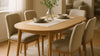 Dining area where a newly swapped oval light-oak table becomes the visual centerpiece, styled with neutral upholstered chairs and natural light.
